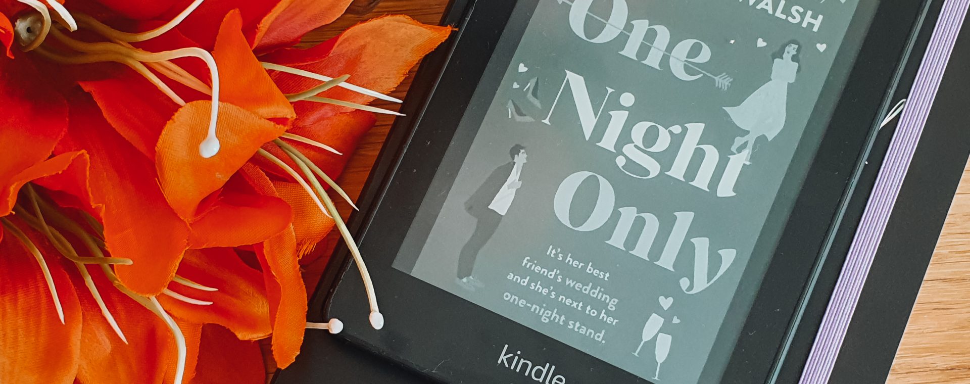 A kindle displaying the cover of One Night Only next to a vase and orange flowers