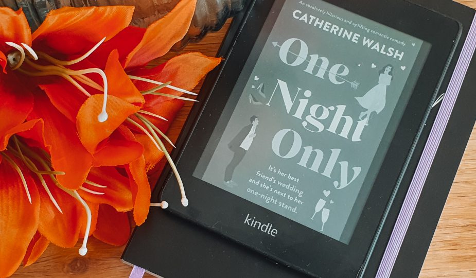 A kindle displaying the cover of One Night Only next to a vase and orange flowers